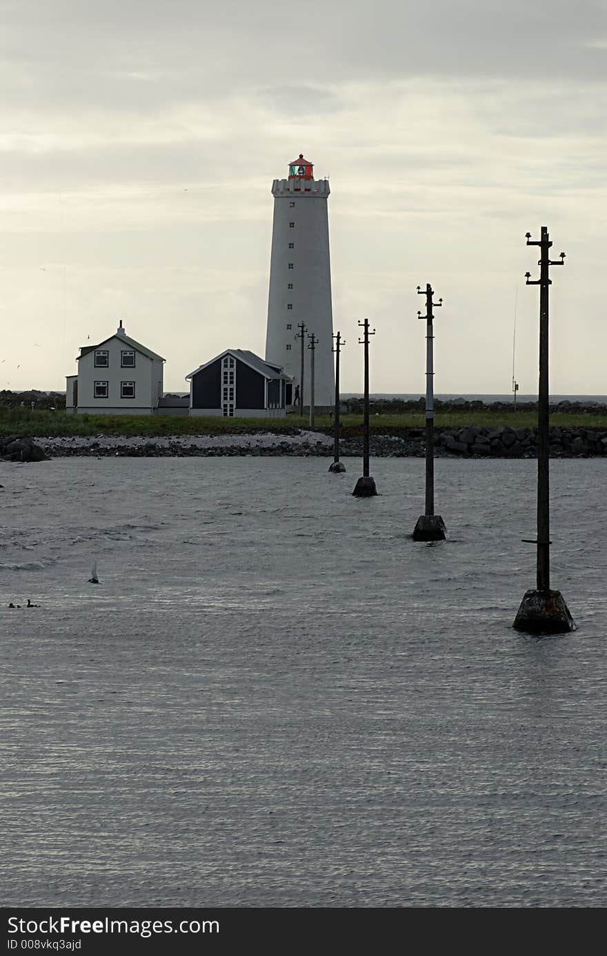 Lighthouse with power transmitting poles leading into in Reykjavik in Iceland.