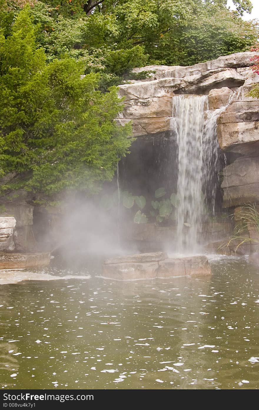 A small waterfall in a greenish colored lake. A small waterfall in a greenish colored lake.