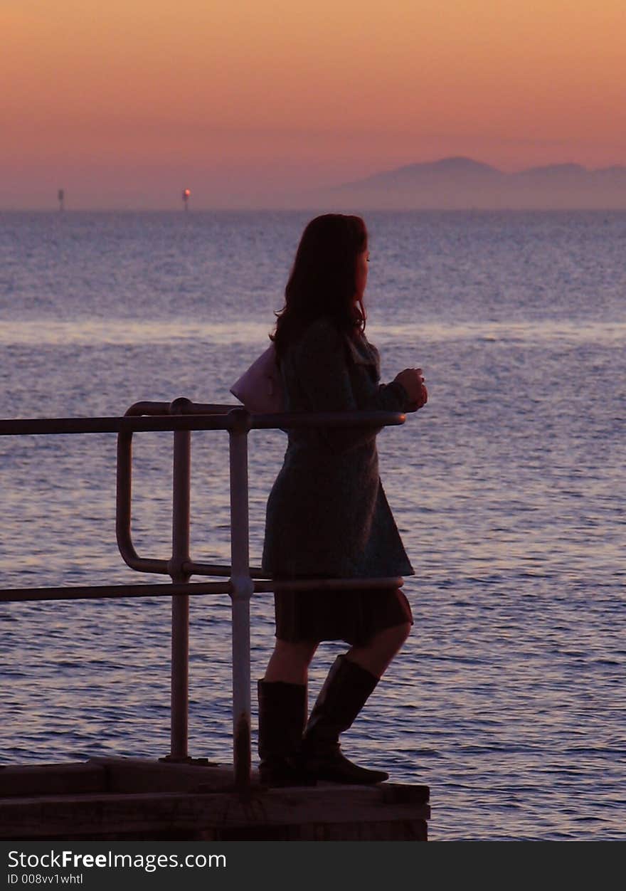 Girl on a pier looking out towards the sea