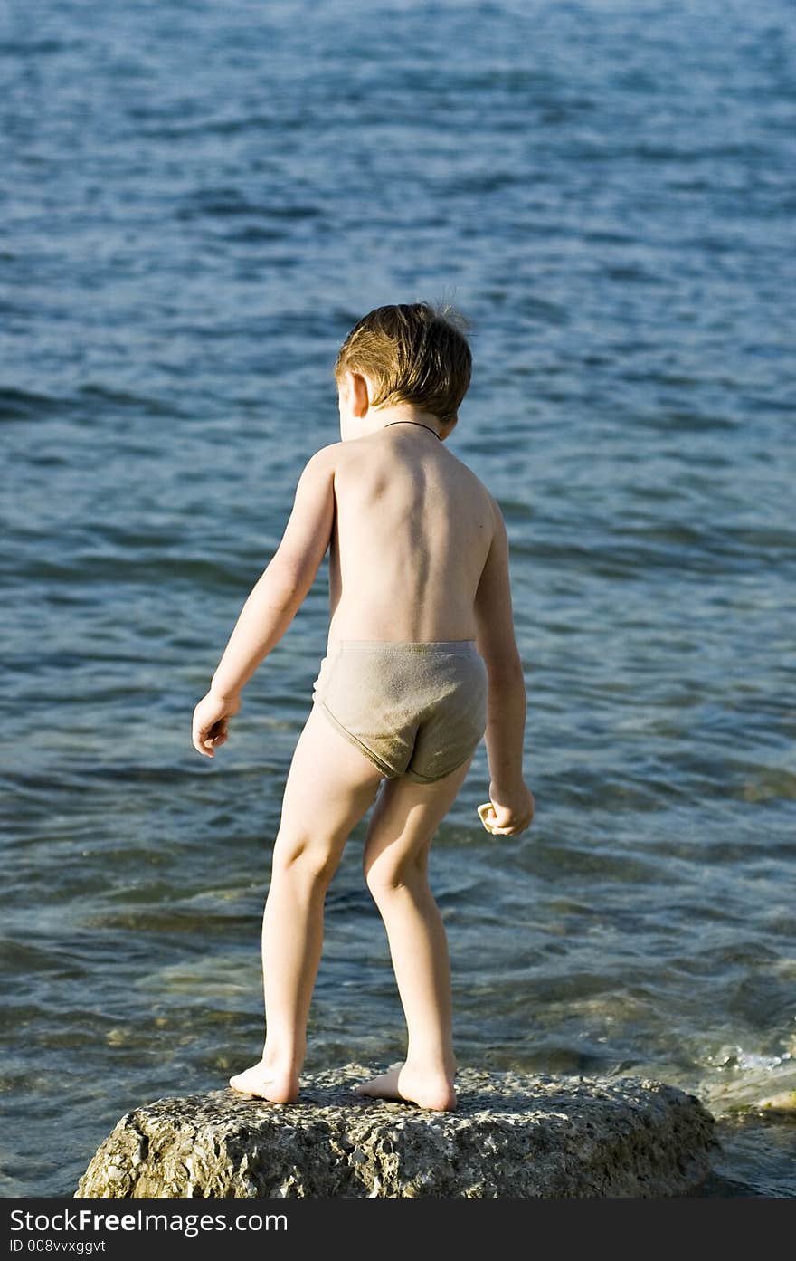 The child plays on a stone beach. The child plays on a stone beach