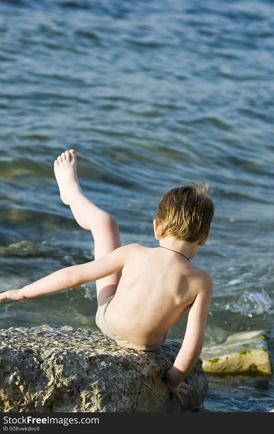 The child plays on a stone beach. The child plays on a stone beach