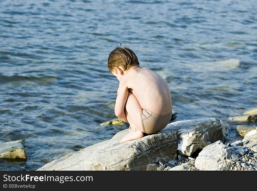 The child plays on a stone beach. The child plays on a stone beach