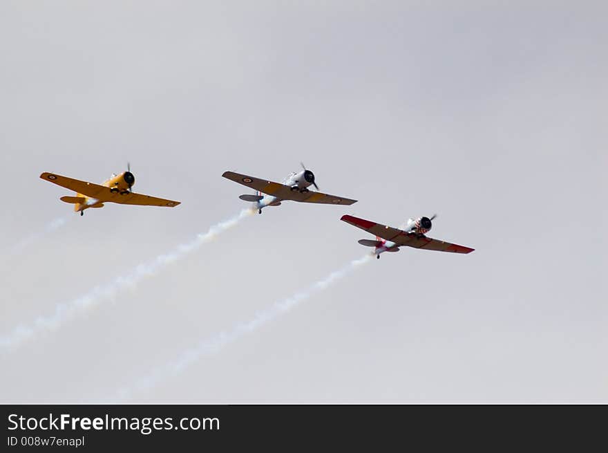 Three Harvard T-6's fly past during an air show. Three Harvard T-6's fly past during an air show.