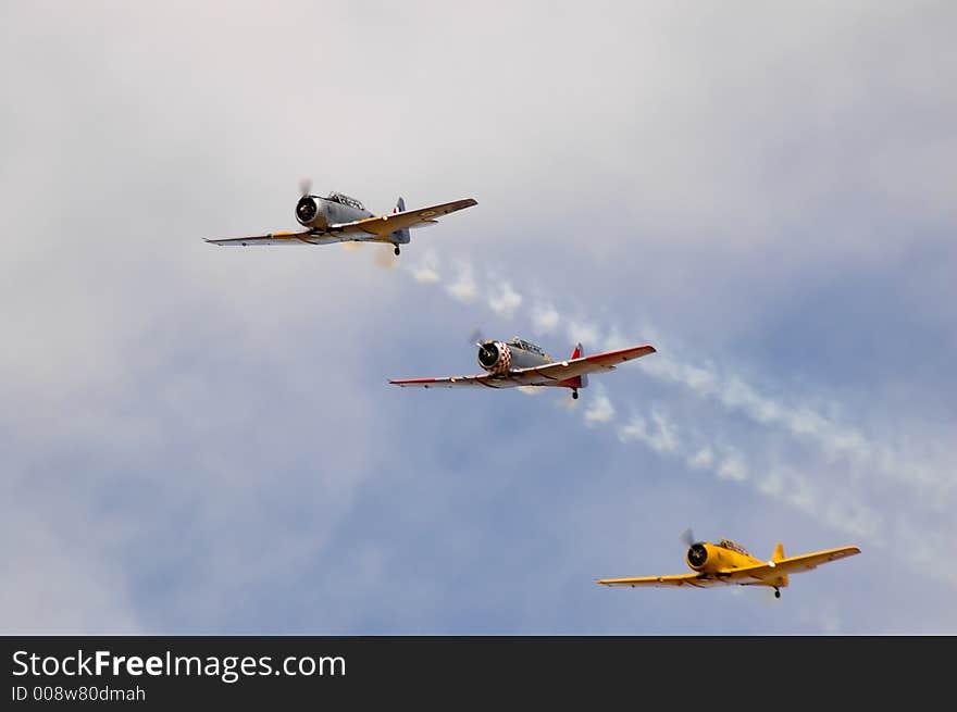 Three Harvard T-6's fly past in formation during an air show. Three Harvard T-6's fly past in formation during an air show.