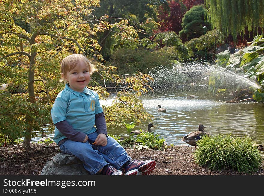 An outdoor portrait of a smiling boy with a pond and ducks. An outdoor portrait of a smiling boy with a pond and ducks