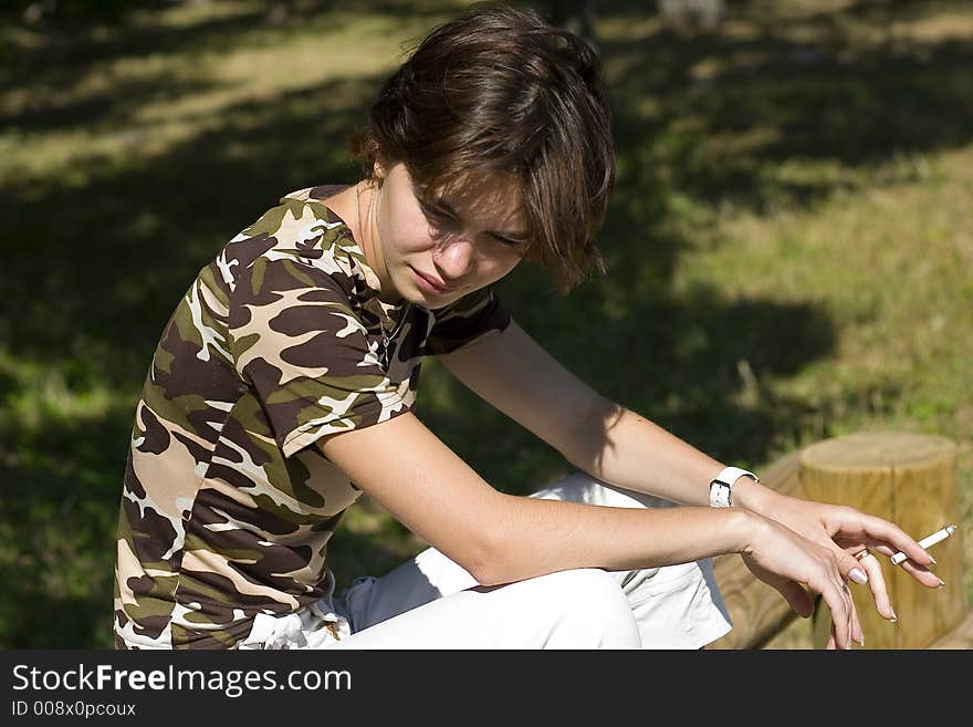 Young woman smoking and thinking in the park. Young woman smoking and thinking in the park