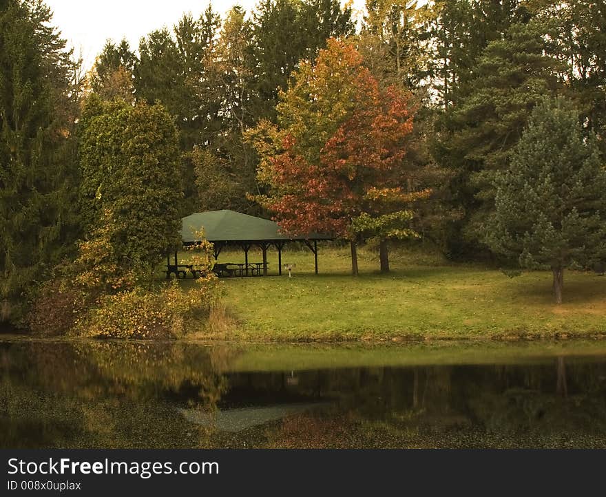 A quite fall scene of a picnic shelter ny a pond with colorful foliage. A quite fall scene of a picnic shelter ny a pond with colorful foliage