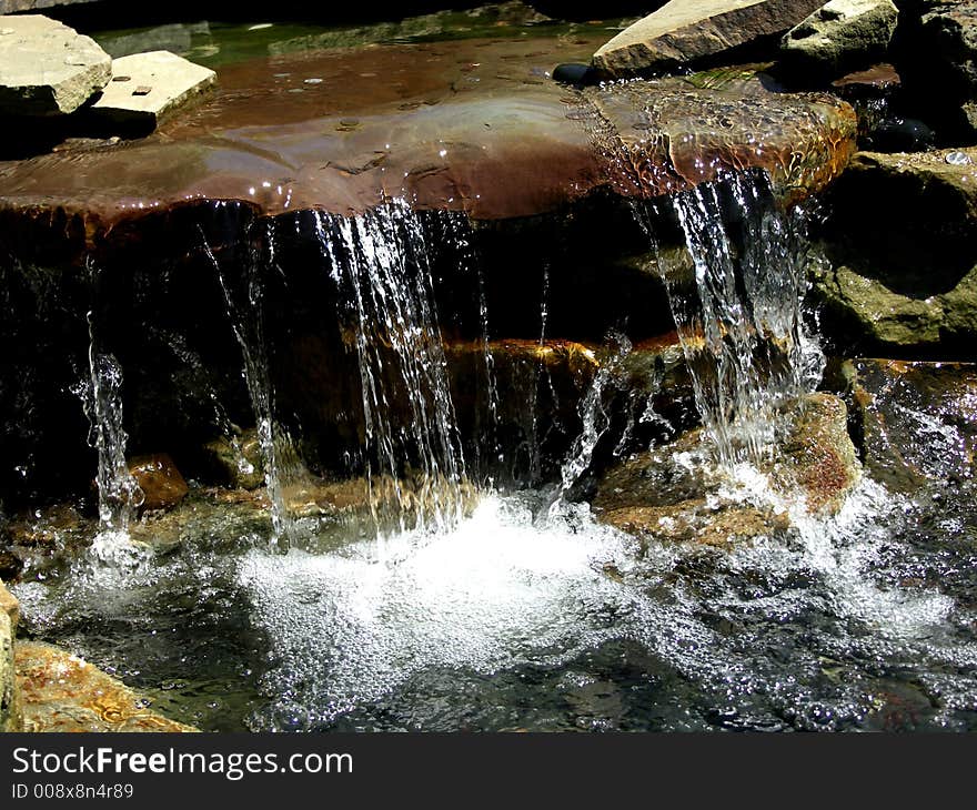 Flowing water over a mini waterfall at the park. Flowing water over a mini waterfall at the park