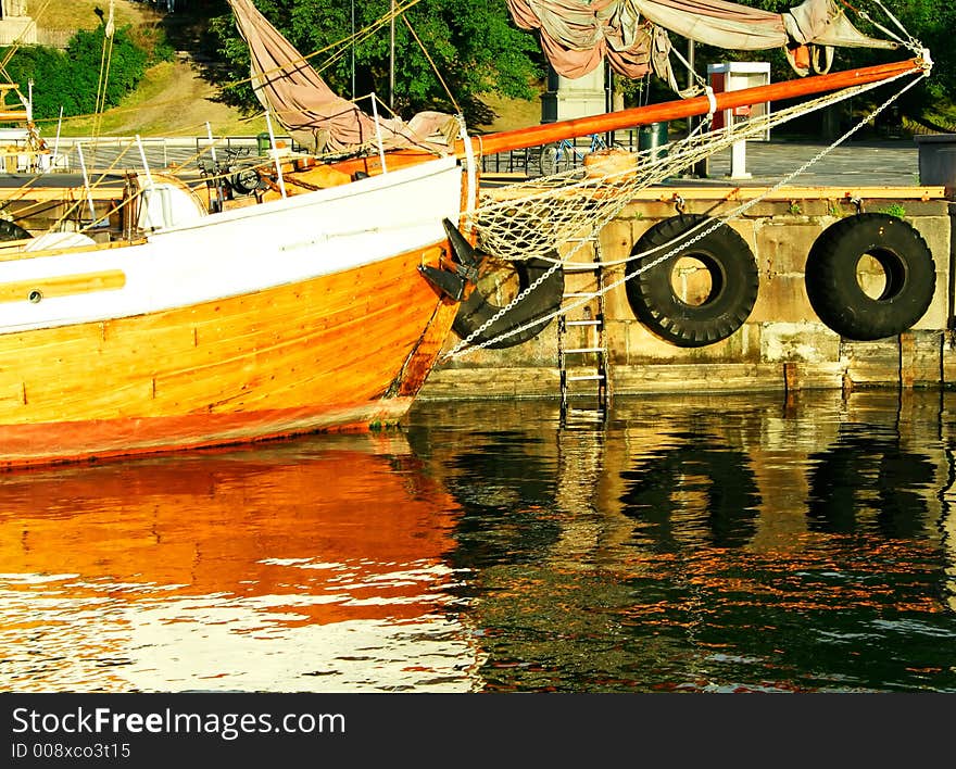 A vintage sailing ship  moored in a harbor. Warm lighting. Beautiful reflexes.