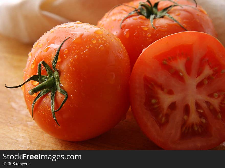 Three tomatoes on a wooden board. Three tomatoes on a wooden board.