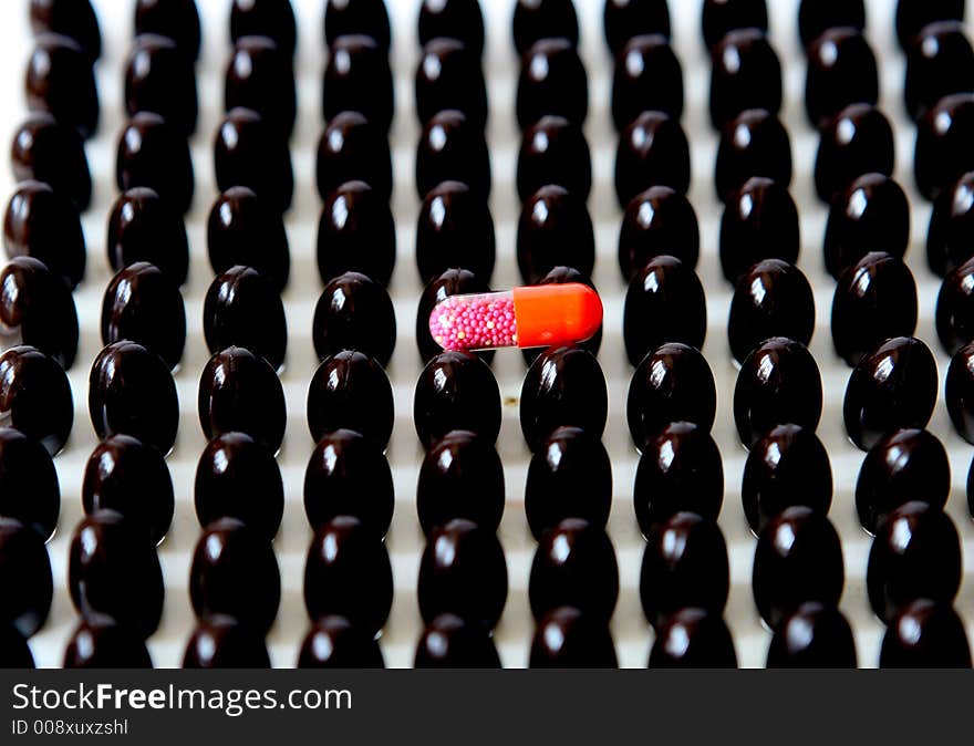 Red capsule upon many brown capsules.