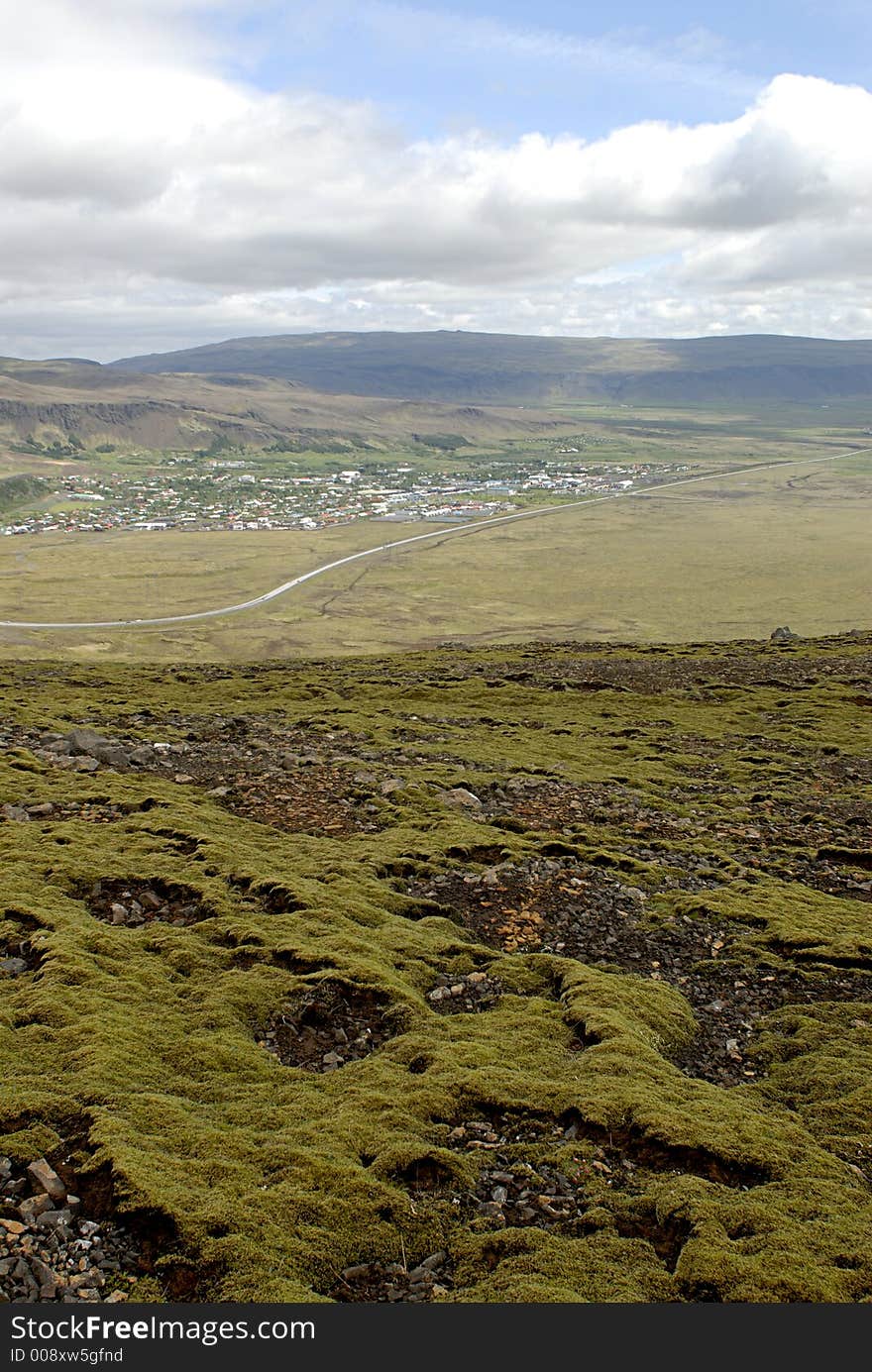 Icelandic landscape - moss on lava field in front and village in valley in background Iceland nature.