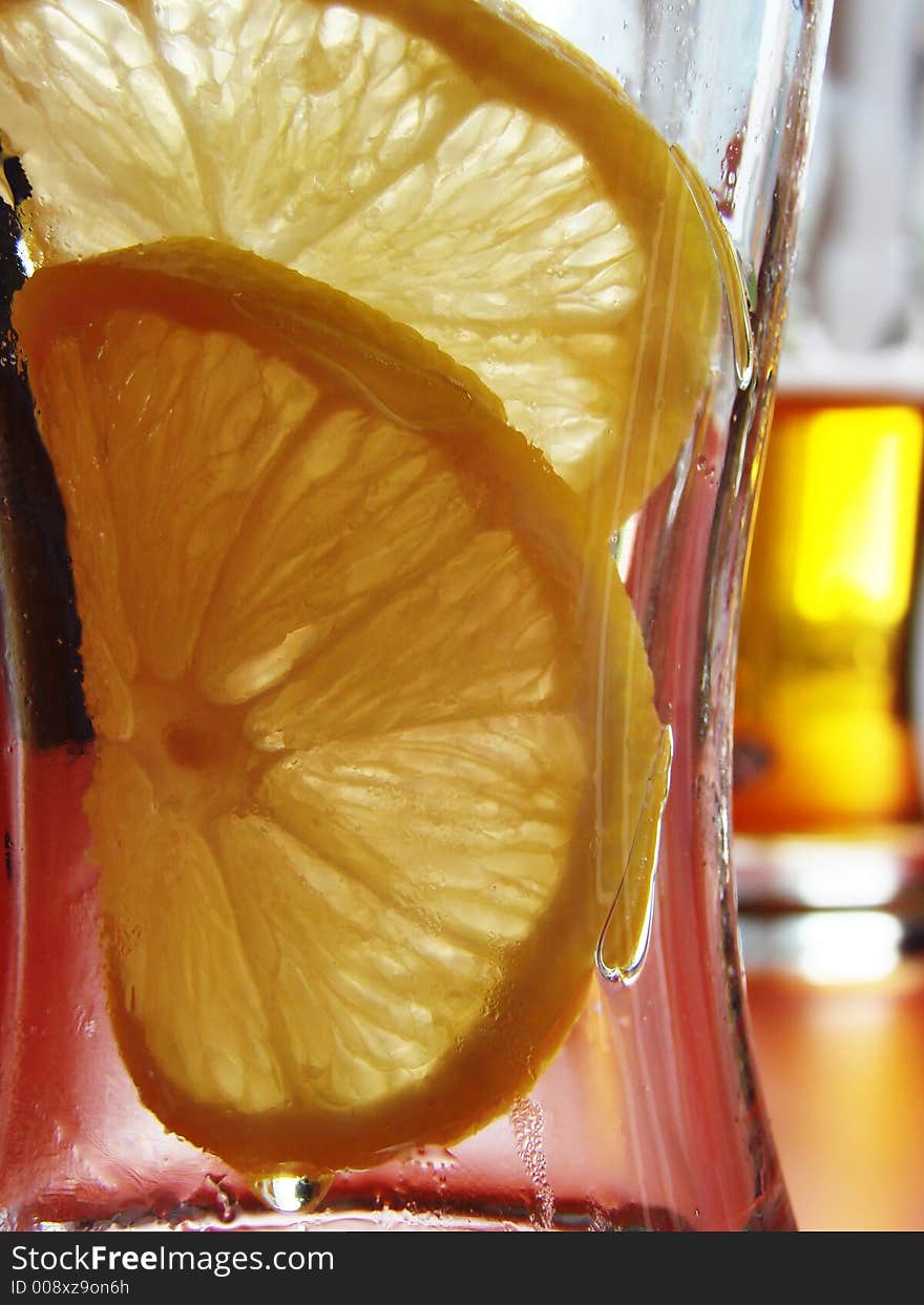 Empty glass from beer with 2 lemon pieces on background with next, full one. Empty glass from beer with 2 lemon pieces on background with next, full one.