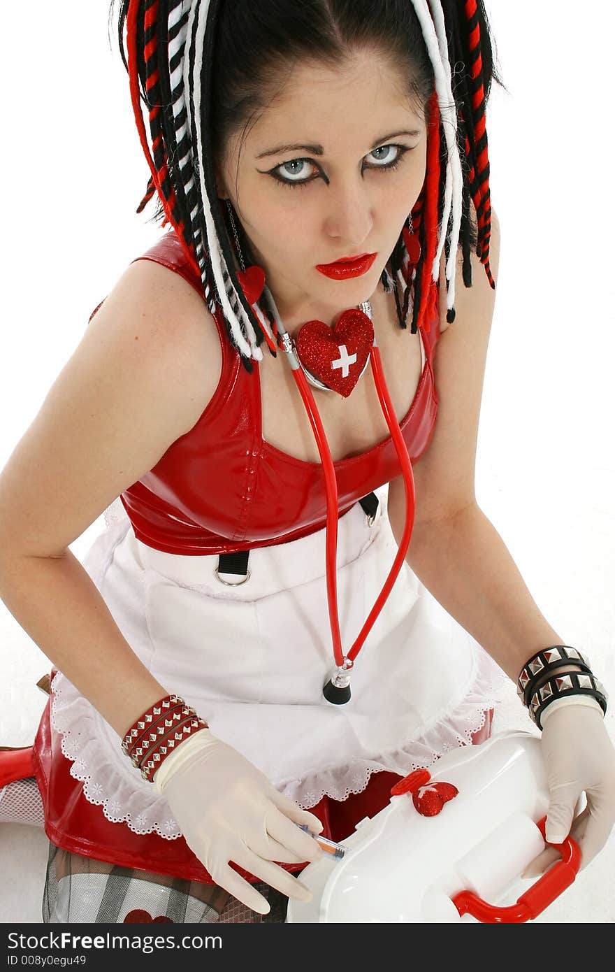 Beautiful young goth nurse sitting, pulling syringe out of medical case.