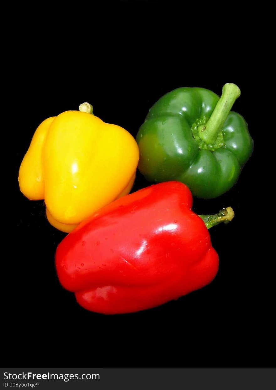 Red, yellow and green sweet peppers on black background