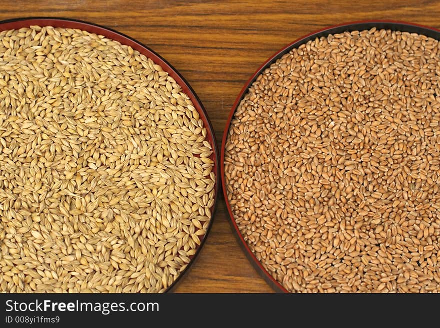 Husked and rough rice on two plates on a wooden table