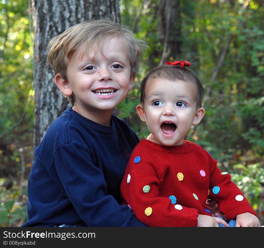 A little girl with her mouth wide-open and a young boy smiling in an outdoor setting. A little girl with her mouth wide-open and a young boy smiling in an outdoor setting.