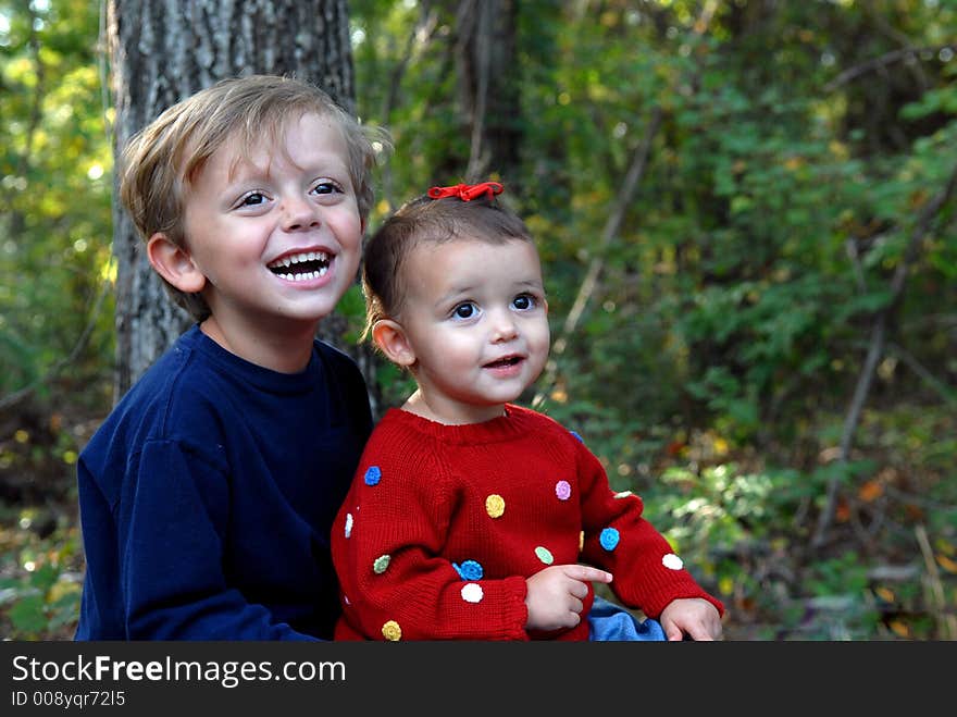 A little girl smiling and a young boy laughting in an outdoor setting. A little girl smiling and a young boy laughting in an outdoor setting.