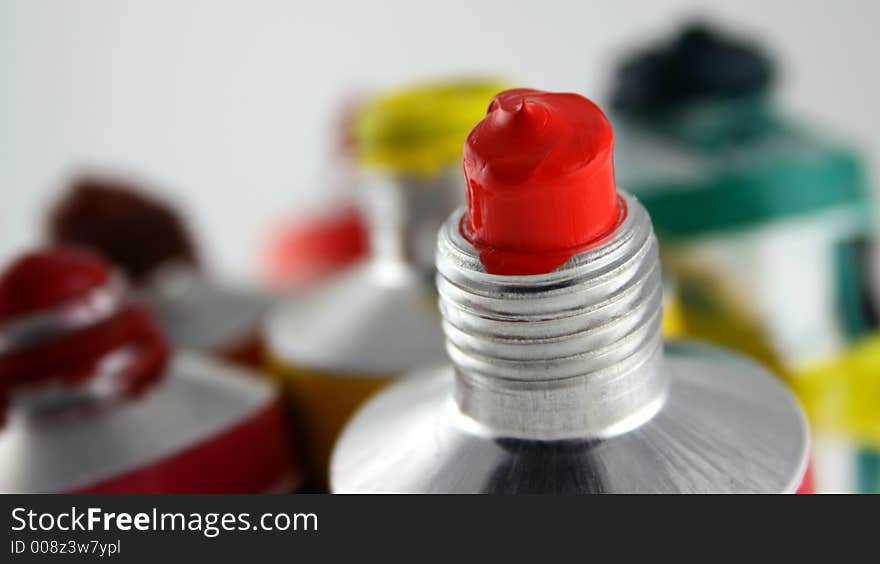 Close up of Red Acrylic Paint Tube, focusing on tube with other colors in the background.