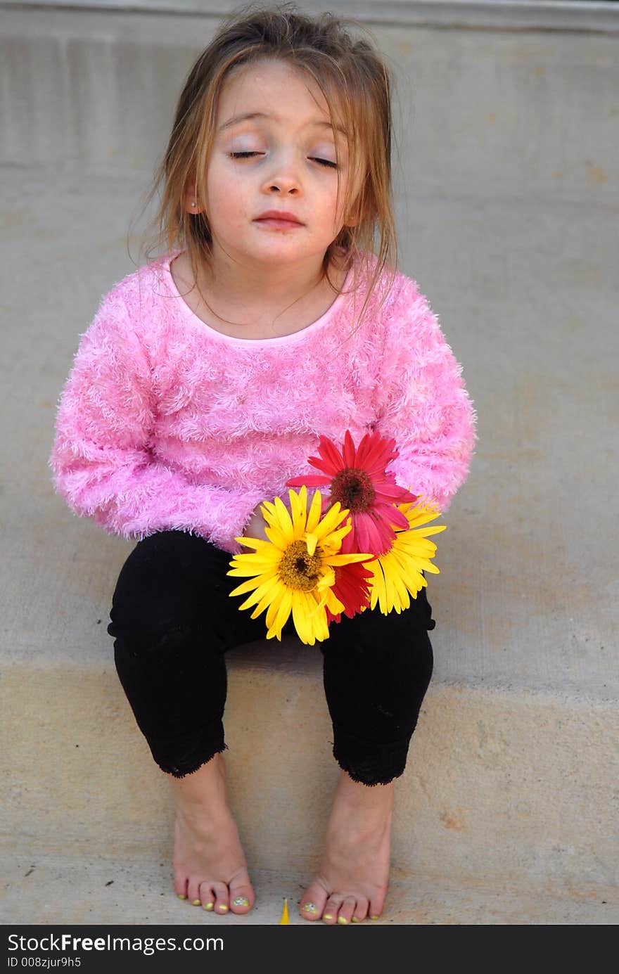 A little girl holding a bouquet of Gerber Daisies she picked from her mother's garden thinking she might be in a little bit of trouble. A little girl holding a bouquet of Gerber Daisies she picked from her mother's garden thinking she might be in a little bit of trouble.