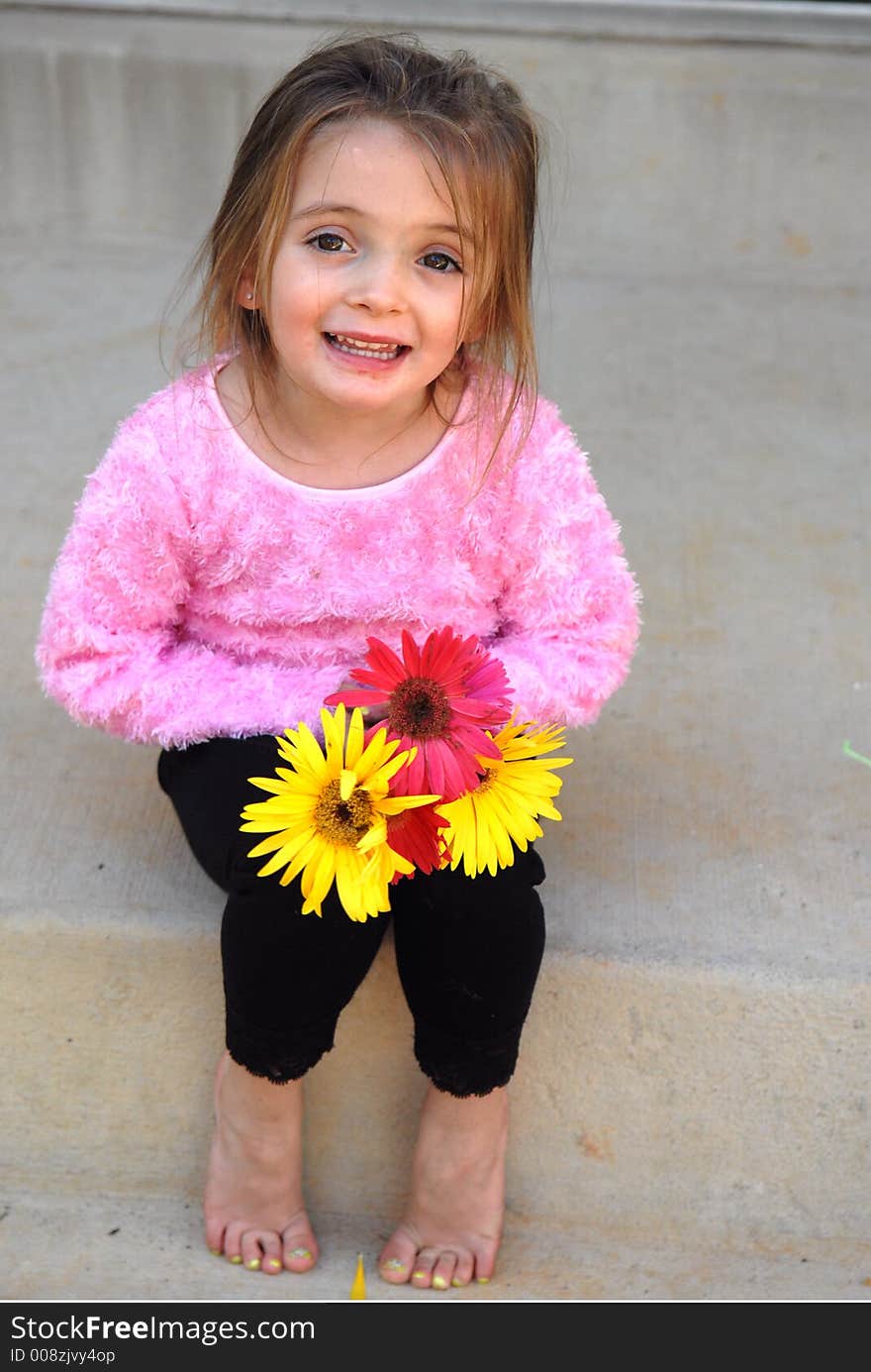 A little girl holding a bouquet of Gerber Daisies she picked from her mother's garden with a sweet smile on her face. A little girl holding a bouquet of Gerber Daisies she picked from her mother's garden with a sweet smile on her face.