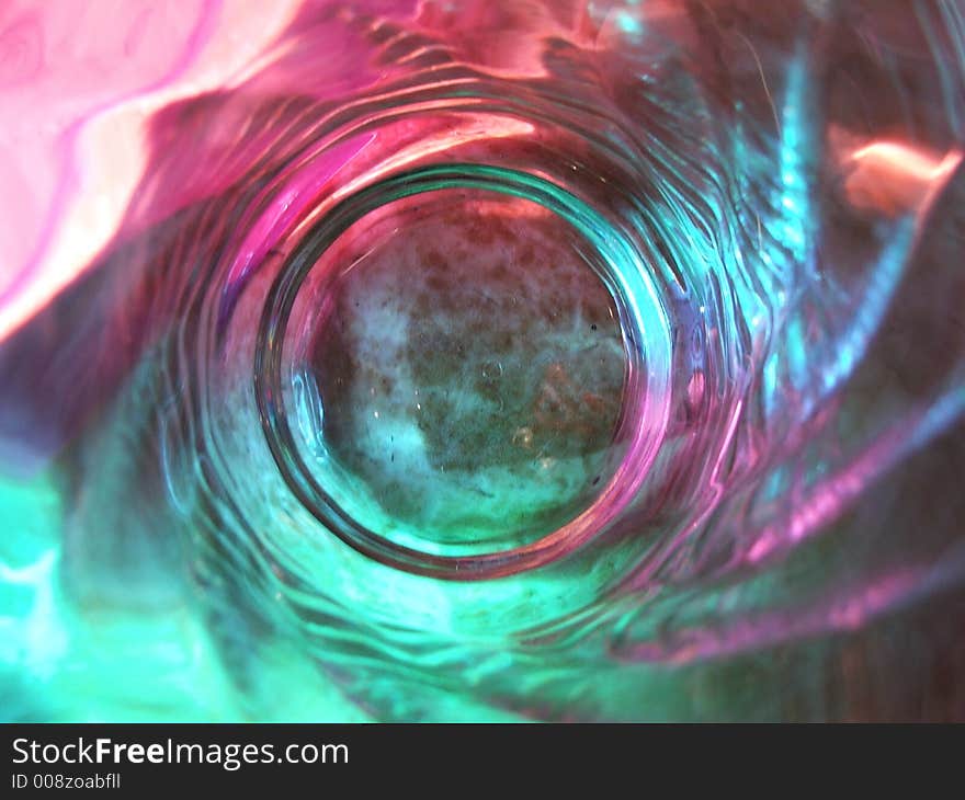 View down into a drinking glass while the light shone through colored filters.  The color & reflection was caught in the details of the glass in a swirl pattern. View down into a drinking glass while the light shone through colored filters.  The color & reflection was caught in the details of the glass in a swirl pattern.