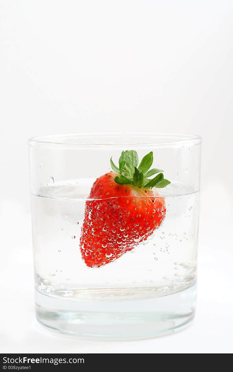 A strawberry into glass with mineral water.