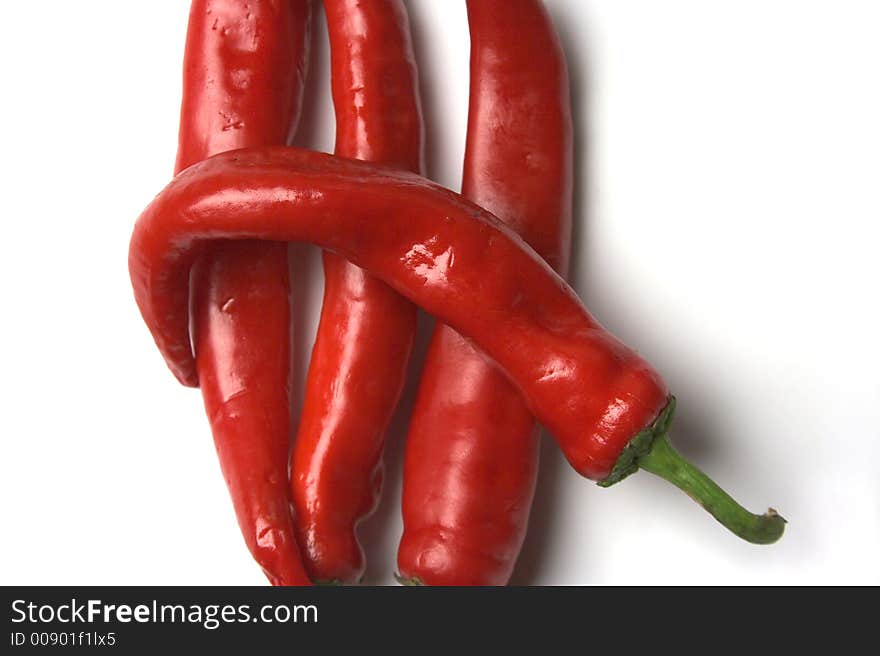 Four red hot chilli peppers closeup on a white background