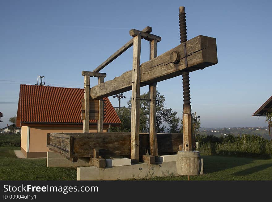 Vintage wine press against blue sky.