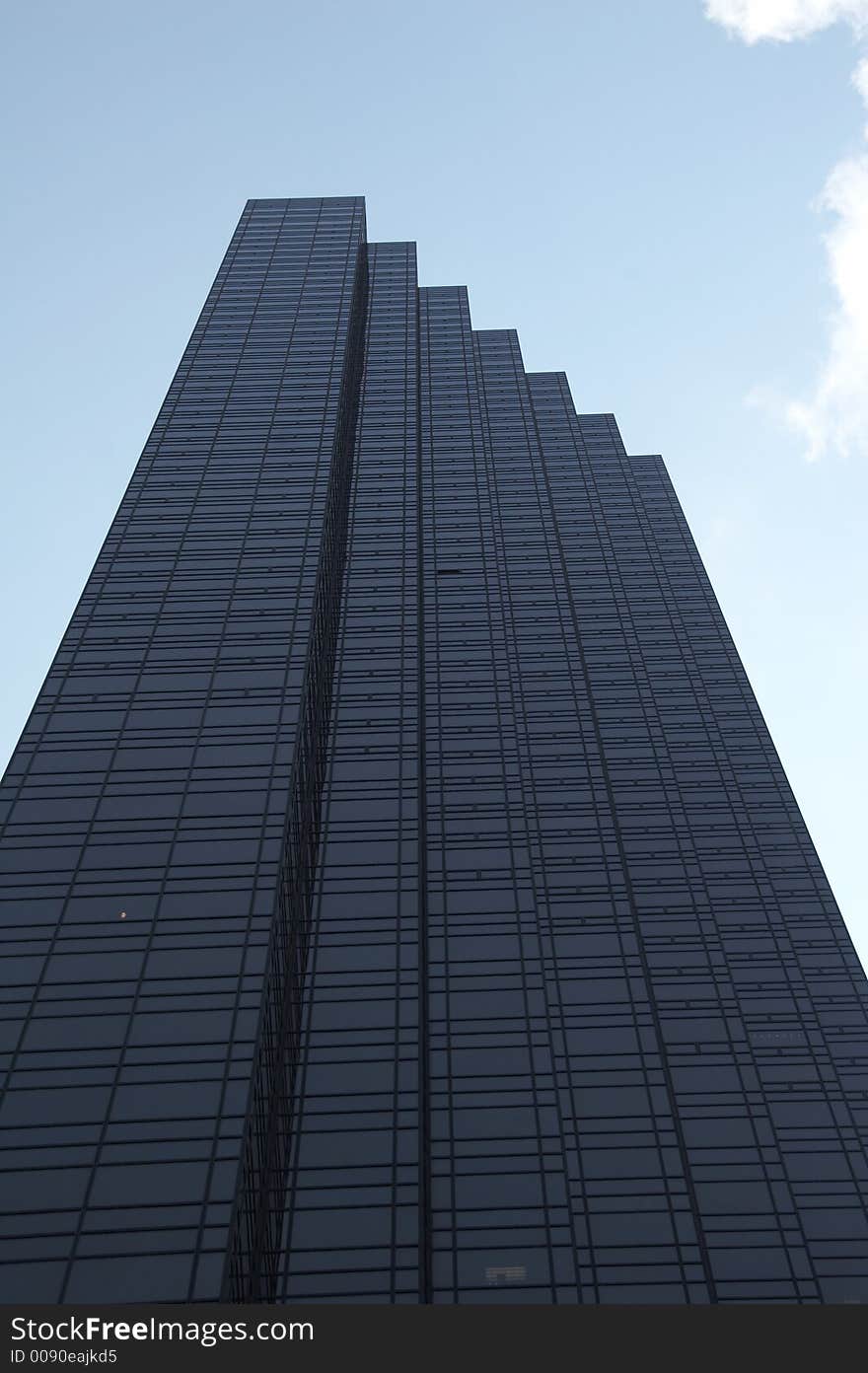 Geometrical skyscraper rises in the cloudless sky