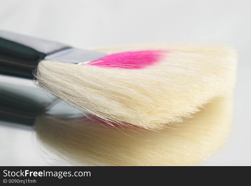 Cosmetic applicator brush lying on a mirror. Cosmetic applicator brush lying on a mirror.