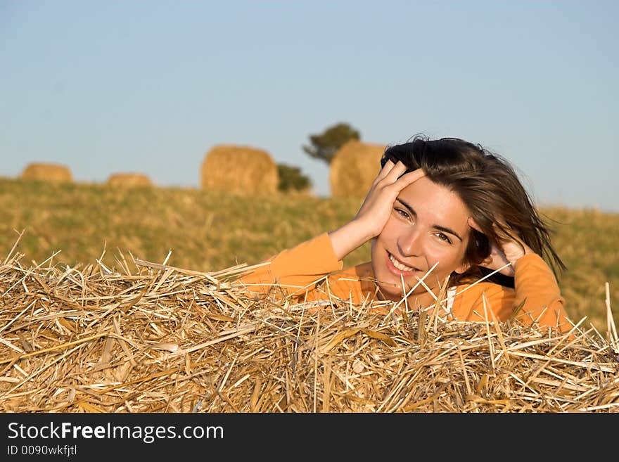 Beautiful woman in a field with hay bales