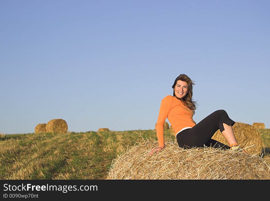 Beautiful woman in a field with hay bales