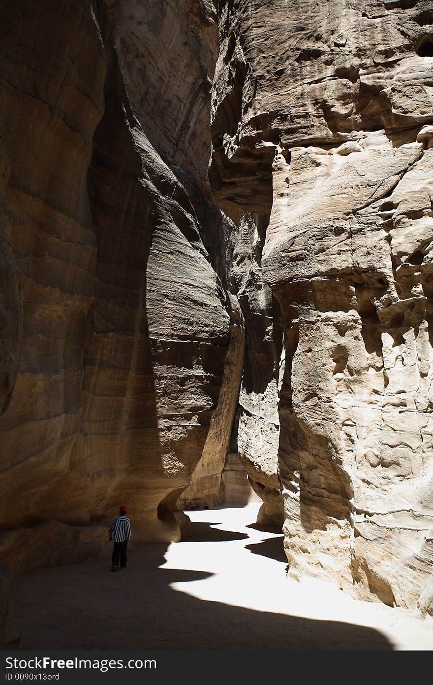 The ancient deserted city of Petra, Jordan, with a boy walking between the edges of the gorge. The ancient deserted city of Petra, Jordan, with a boy walking between the edges of the gorge