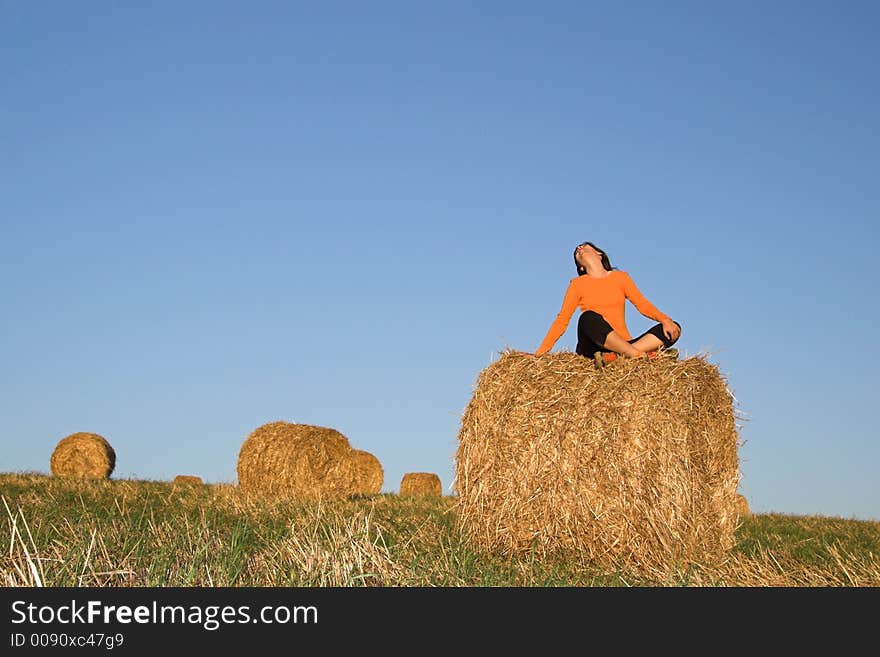 Beautiful woman seated in hay bale