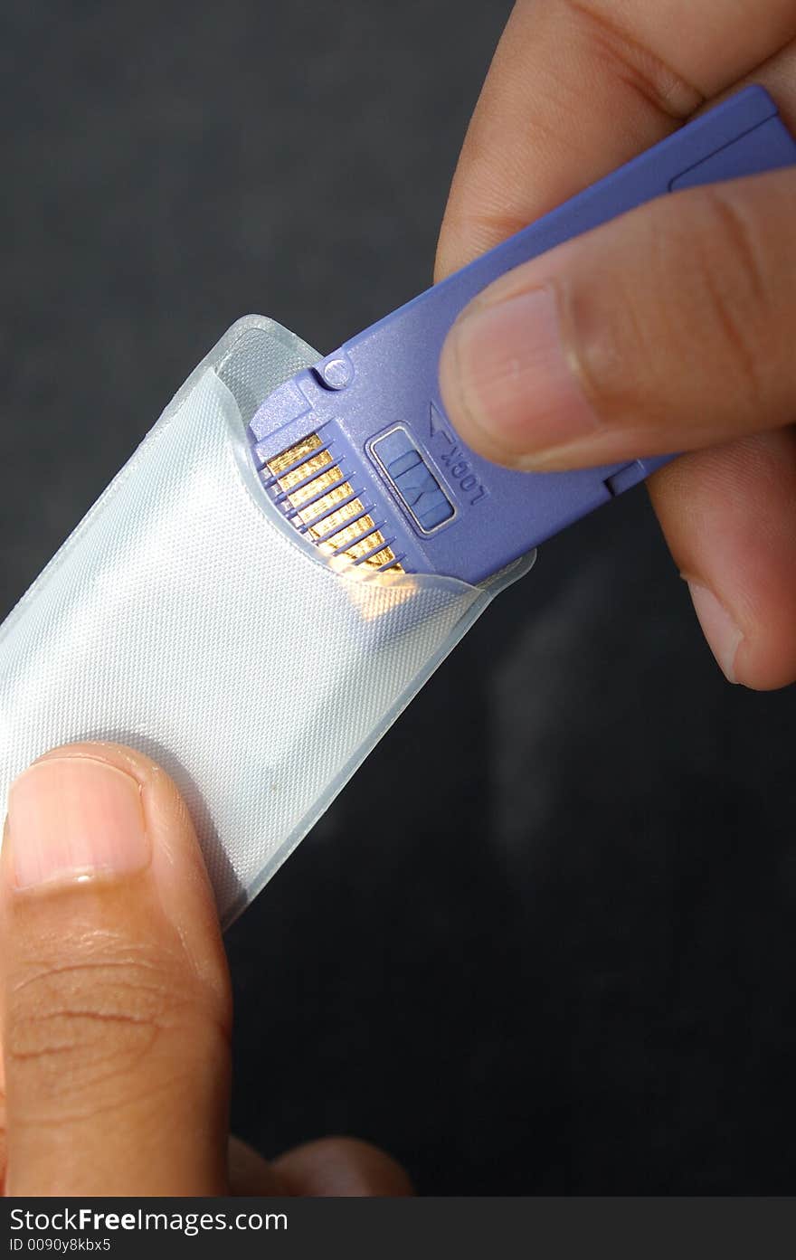 A girl puts a memory card into it's protective plastic case after use.