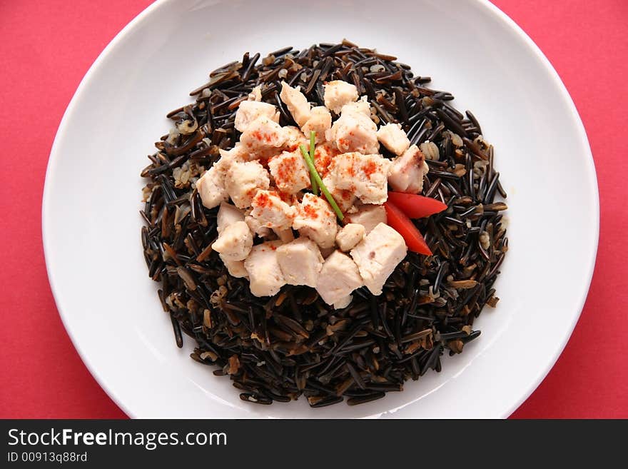 Black rice with boiled chicken breast on a white plate. Black rice with boiled chicken breast on a white plate.