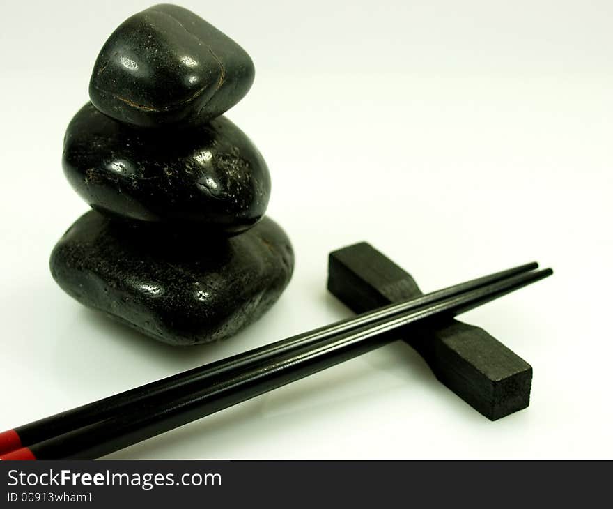 Hot stones and black chopstick on a pure white background. Hot stones and black chopstick on a pure white background