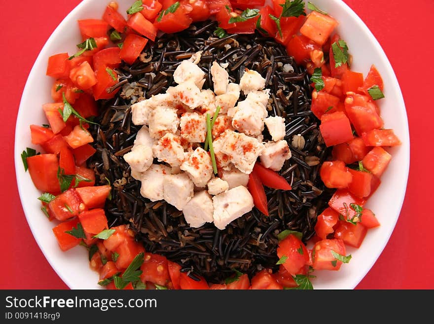 Black rice with boiled chicken breast and tomatoes on a white plate. Black rice with boiled chicken breast and tomatoes on a white plate.