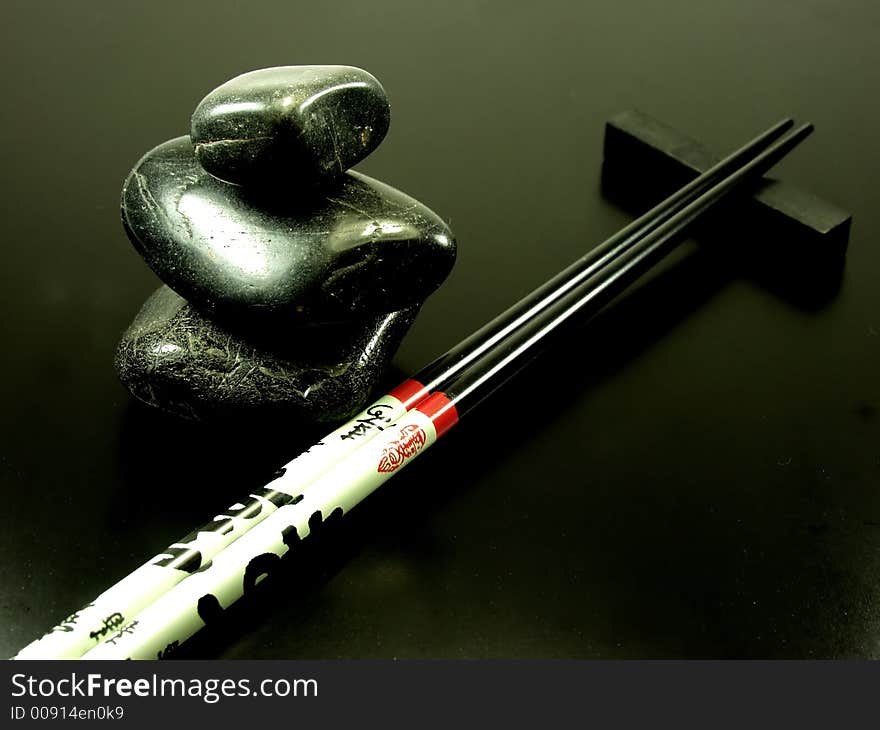 Black hot stones whit decorated chopsticks on black background. Black hot stones whit decorated chopsticks on black background