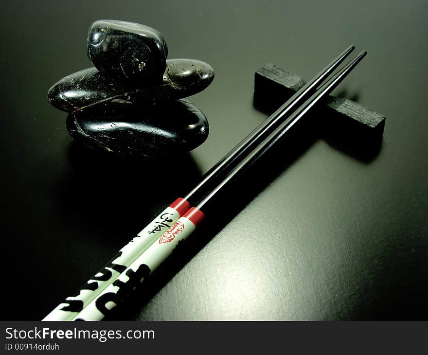 Hot stones and black chopsticks on black background. Hot stones and black chopsticks on black background