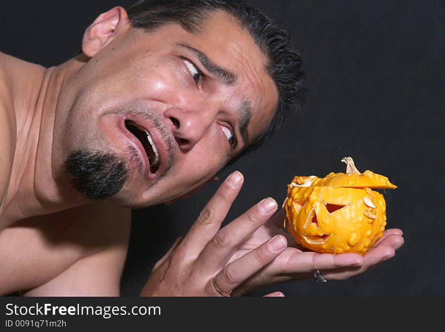 Portrait of a man scared of little halloween pumpkin