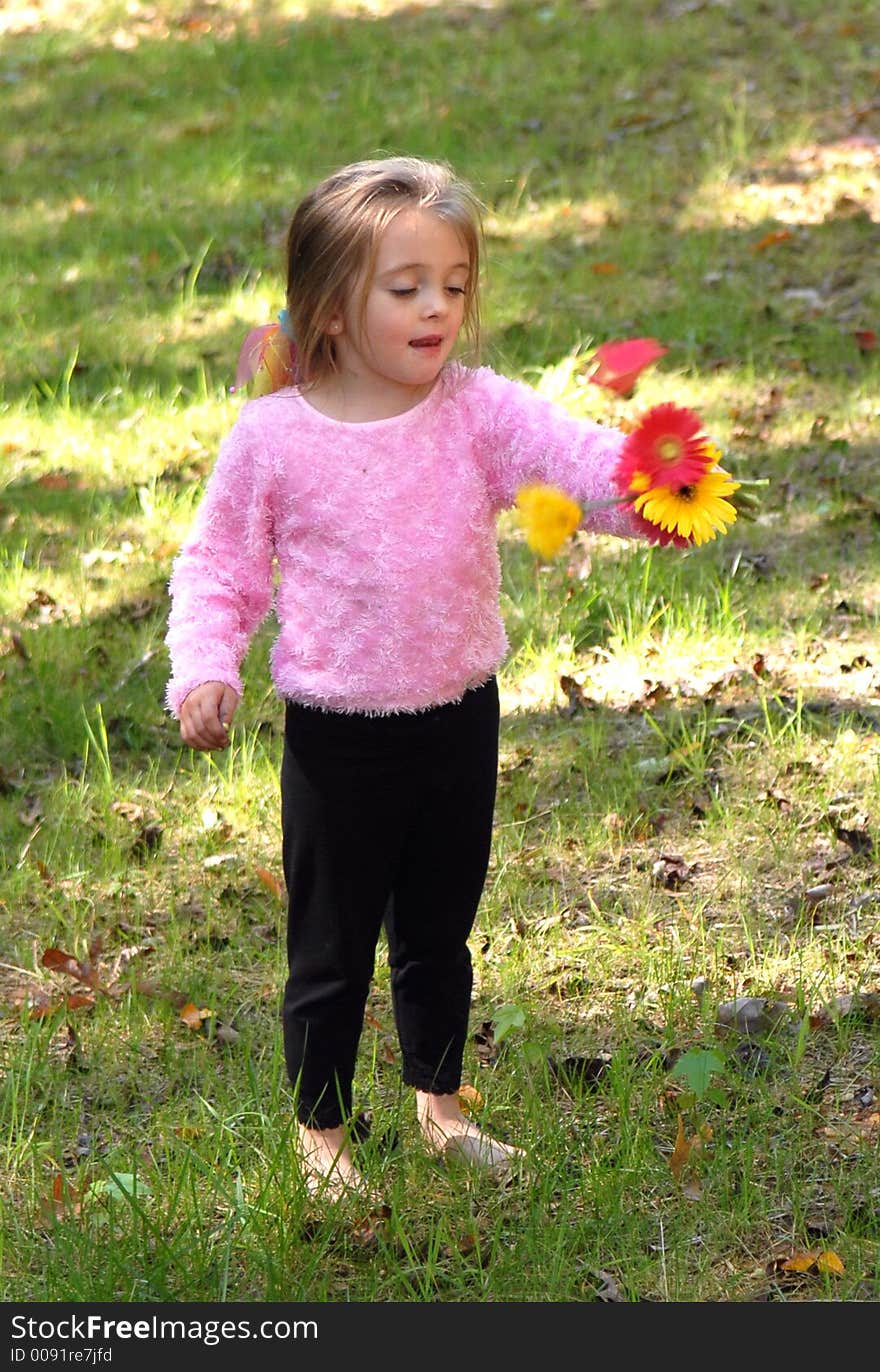 A little girl standing by a tree barefoot holding a bouquet of daisies she just picked from the garden. A little girl standing by a tree barefoot holding a bouquet of daisies she just picked from the garden.