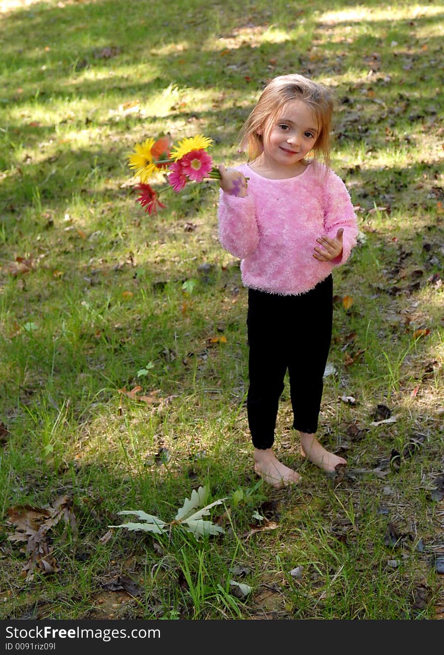 A little girl standing barefoot holding a bouquet of daisies she just picked from the garden. A little girl standing barefoot holding a bouquet of daisies she just picked from the garden.