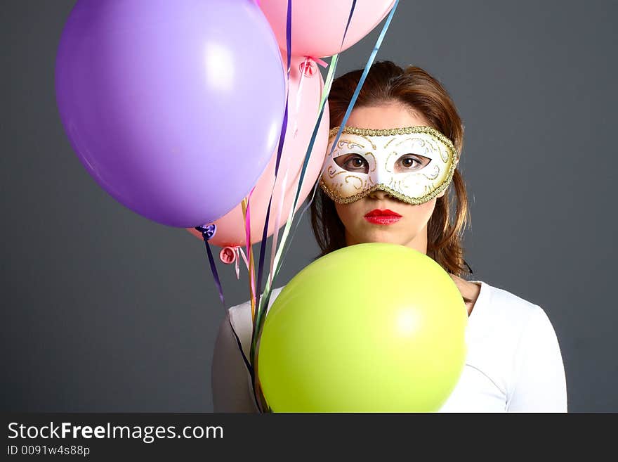 Brunette wearing a mask and multi-colored balloons. Brunette wearing a mask and multi-colored balloons