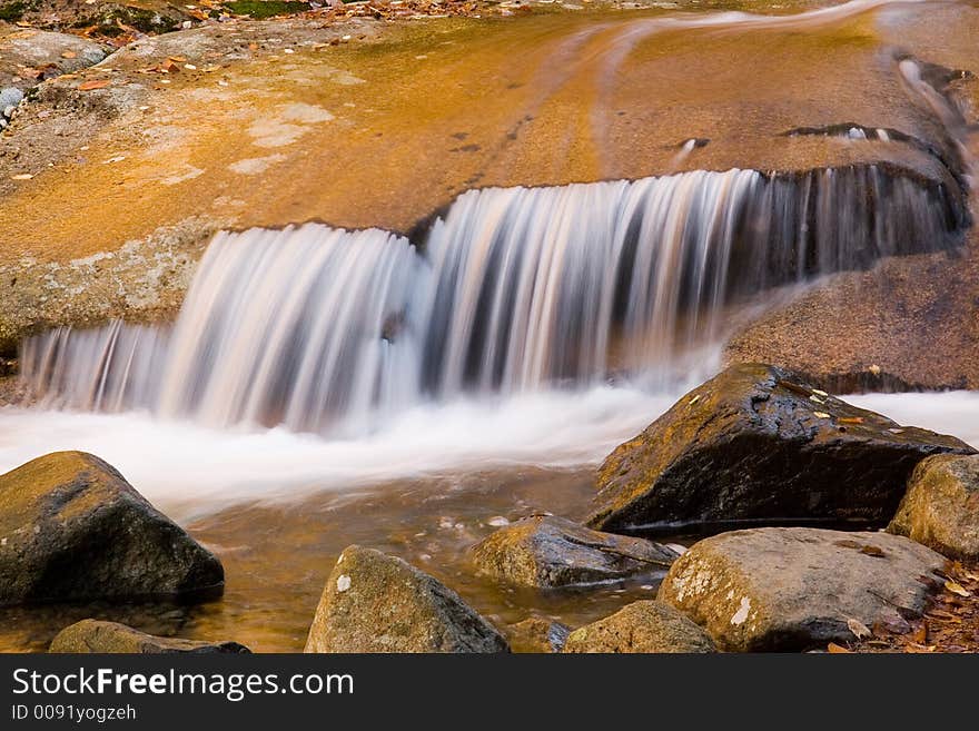 Autumn stream flows over smooth brown rocks. Autumn stream flows over smooth brown rocks.