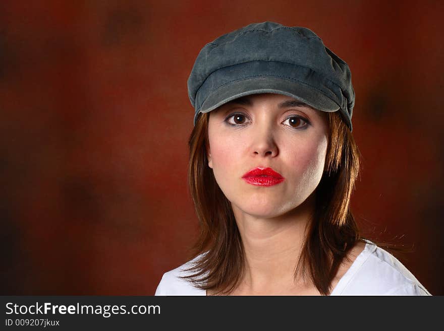 Brunette with grey cap and white shirt in front of red backdrop. Brunette with grey cap and white shirt in front of red backdrop