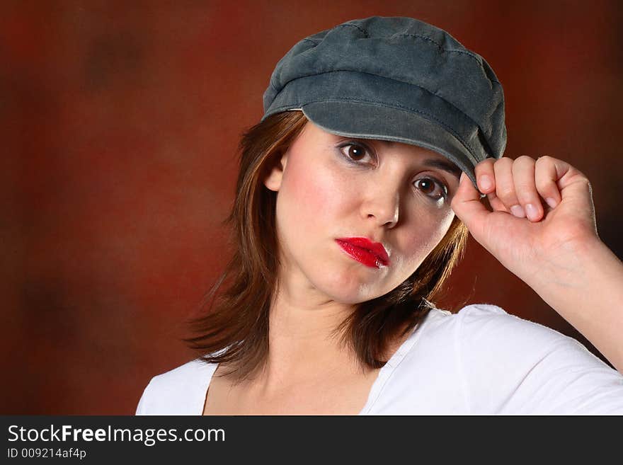 Brunette with grey cap and white shirt in front of red backdrop. Brunette with grey cap and white shirt in front of red backdrop