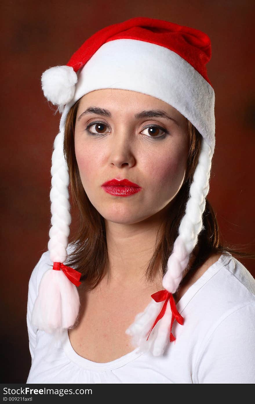 Brunette wearing a santa hat in front of red backdrop. Brunette wearing a santa hat in front of red backdrop