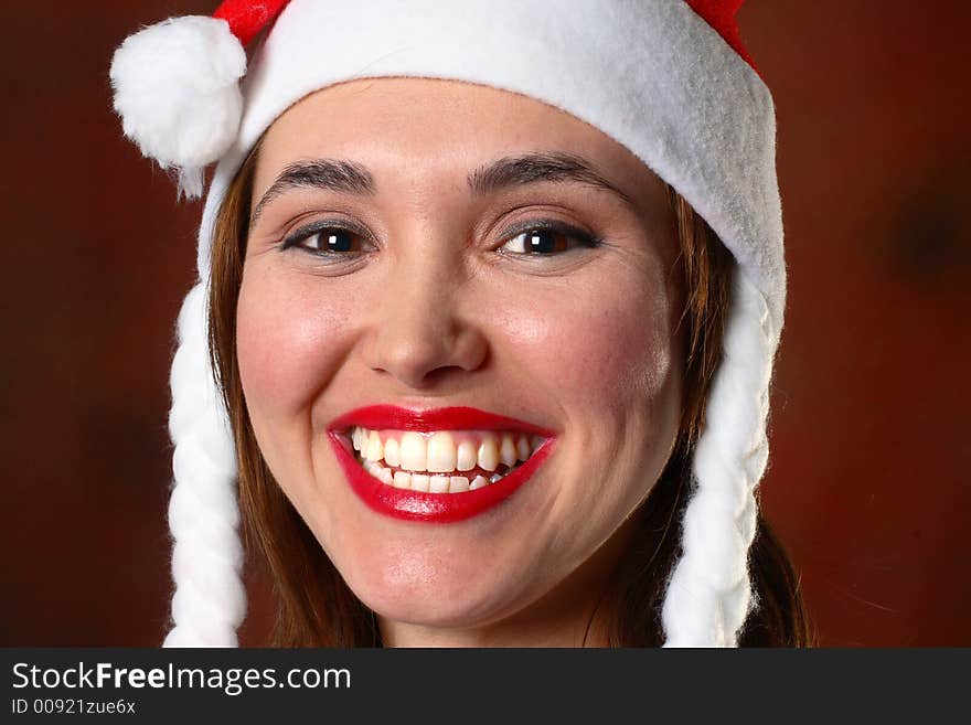 Brunette wearing a santa hat in front of red backdrop. Brunette wearing a santa hat in front of red backdrop